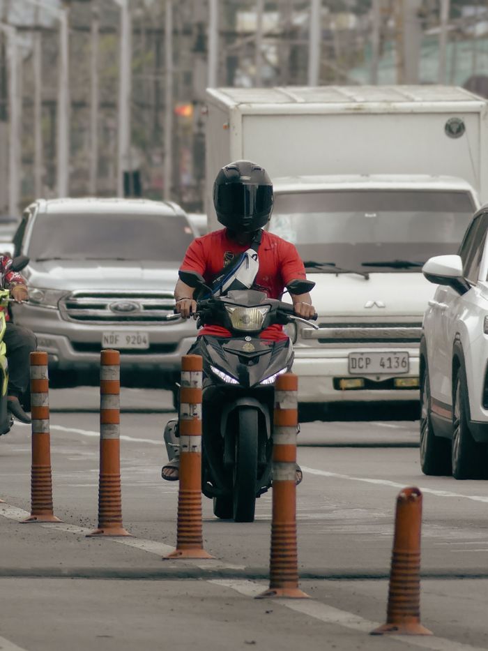 Motorcyclist rides through busy Makati city street, showcasing urban traffic dynamics.